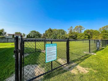 A sign on a fence reads "DOG PARK RULES".